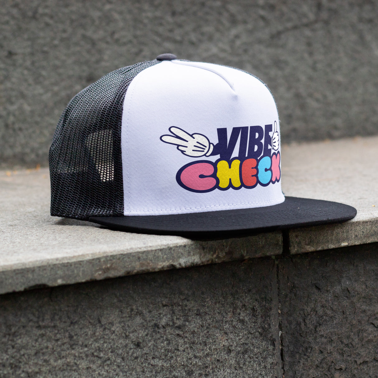 Black and white cap with colorful text design on a concrete surface using ricoma dtf printer